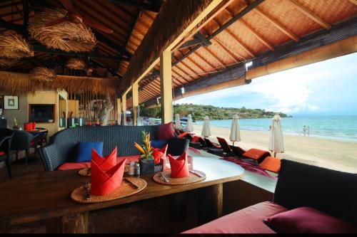 un restaurante con mesa y sillas en la playa en Kupu Kupu Jimbaran Beach Hotel & Spa by L’Occitane en Jimbaran