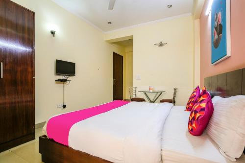 a bedroom with a large white bed with pink pillows at Collection O Hotel Royal Suits in Gurgaon