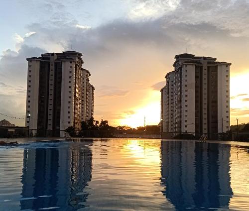 two tall buildings with the sunset in the background at Cozy Suria Kipark Damansara 3R2B Apartment Max 8pax in Kuala Lumpur