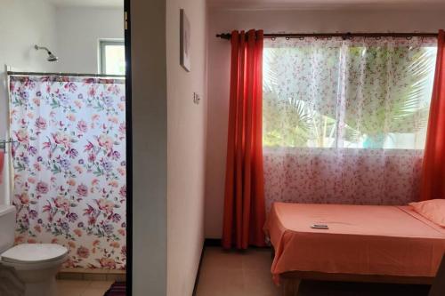 baño con aseo y ventana con cortinas en Coastal Casita, en Bejuco