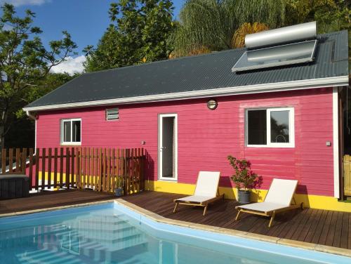 布雍特的住宿－Kaz Kalina - Gîtes avec piscine partagée，粉红色的房子,配有两把椅子和游泳池