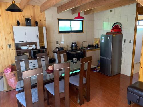 a kitchen with a table and chairs and a refrigerator at Cabaña Coñaripe in Coñaripe