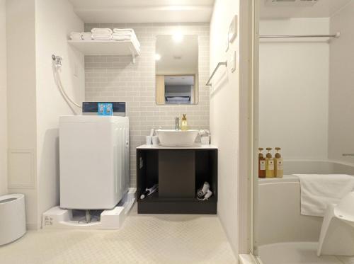 a white bathroom with a sink and a tub at ESLEAD HOTEL Osaka Tsuruhashi in Osaka