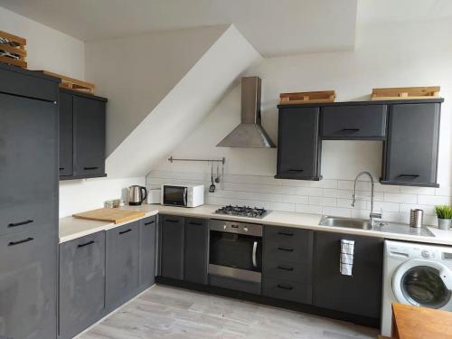 a kitchen with black cabinets and a stove top oven at Large 2 Bedroom City Centre Apartment + Parking in Preston