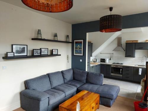 a living room with a blue couch and a kitchen at Large 2 Bedroom City Centre Apartment + Parking in Preston