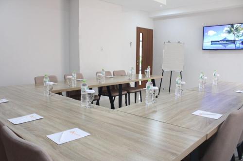 AZKA HOTEL Managed by Salak Hospitality في جاكرتا: قاعة اجتماعات مع طاولة وكراسي خشبية كبيرة