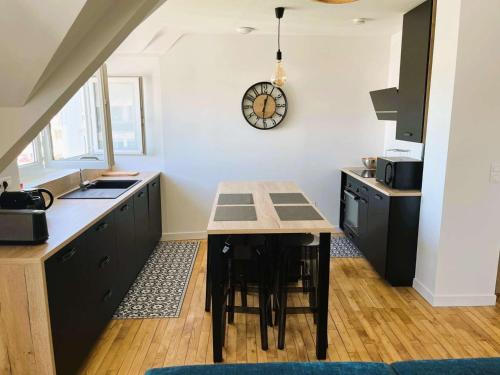 une cuisine avec une table et une horloge au mur dans l'établissement Appartement Confort à Bénodet: Plage et Commerces à Pied, Parking Privé, 4 Pers. - FR-1-481-152, à Bénodet