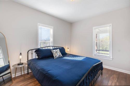 a bedroom with a blue bed and two windows at Downtown home! Walk to Bulls Stadium, DPAC & food in Durham
