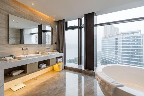 ein Badezimmer mit einer Badewanne, 2 Waschbecken und einem großen Fenster in der Unterkunft Atour Hotel Tonglu Fuchunjiang in Tonglu