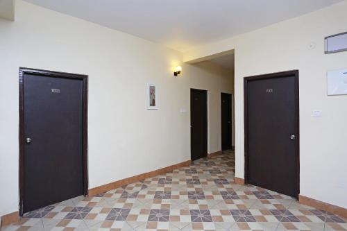 a hallway with three black doors and a tile floor at Stellar Resort in Bhubaneshwar