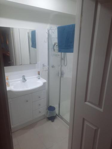 La salle de bains blanche est pourvue d'une douche et d'un lavabo. dans l'établissement Cock or Two Kink House, à Cockatoo