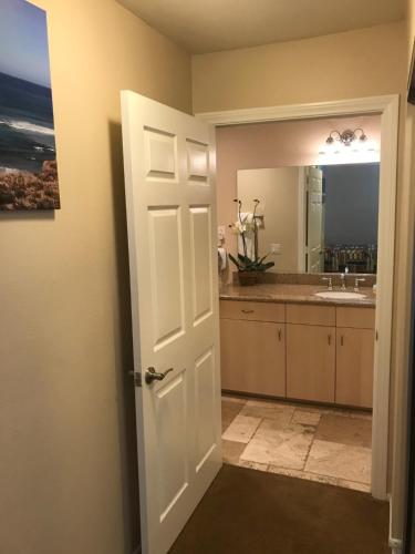 a bathroom with a sink and a white door at Amazing Location - Large and Luxurious 1 Bedroom Beach Condo By Beaches and Attractions in Solana Beach