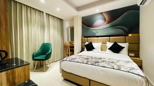 a hotel room with a bed and a green chair at Travellers Hotel in New Delhi