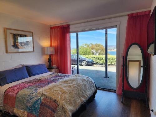 um quarto com uma cama, um espelho e uma janela em Waterfront Abode - 2 bedrooms em Hobart