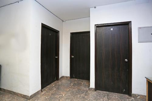 two black doors in a room with white walls at OYO Hotel Kohinoor in New Delhi