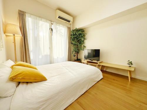 - une chambre avec un grand lit blanc et une télévision dans l'établissement Picolo Hakata, à Fukuoka