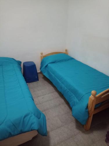 two beds in a room with blue sheets at Lo de Nelly in Puerto Madryn