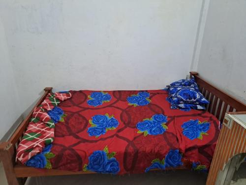 a bed with a redspread with blue flowers on it at Apple Hotel Rooms in Vagamon