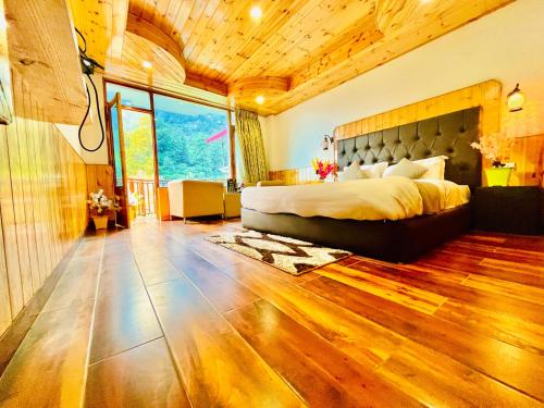a bedroom with a large bed and a large window at Himalayan Nature Walk Resort, Manali in Manāli