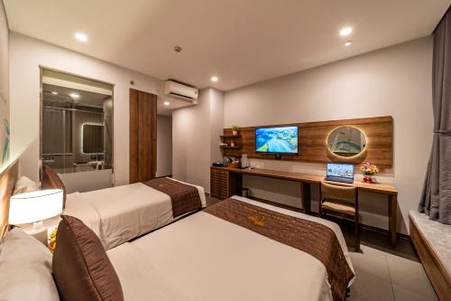 a hotel room with two beds and a desk with a computer at Thanh Long Hotel - Tra Khuc in Ho Chi Minh City