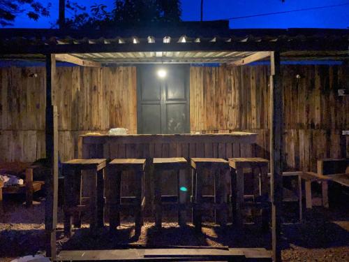 a wooden pergola with a table and chairs at night at Vuglamping in Hue