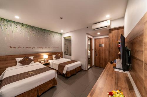 um quarto de hotel com duas camas e uma televisão em Thanh Long Hotel - Tra Khuc em Ho Chi Minh