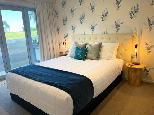 a bedroom with a large white bed with a window at Longitude Apartments Raglan in Raglan