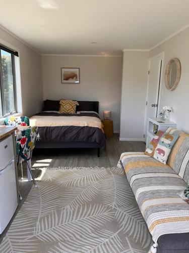 a living room with a bed and a couch at Kowhai Landing Beach Cabin in Otaki Beach
