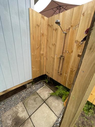 una valla de madera con una puerta con sombrilla en Kowhai Landing Beach Cabin, en Otaki Beach