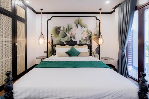 a bedroom with a large bed with a painting on the wall at Cozy An Boutique Hotel Luangprabang in Luang Prabang