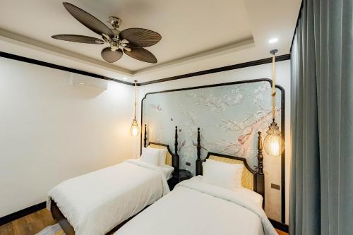 two beds in a room with a ceiling fan at Cozy An Boutique Hotel Luangprabang in Luang Prabang
