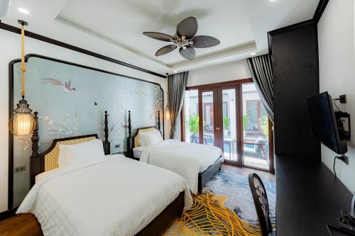 a bedroom with two beds and a ceiling fan at Cozy An Boutique Hotel Luangprabang in Luang Prabang