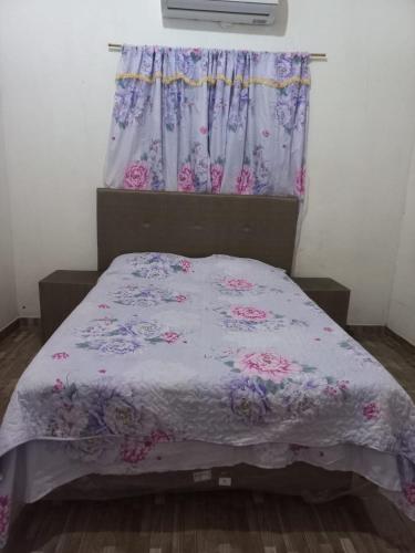 een slaapkamer met een bed met een paars dekbed en een raam bij HOSPEDAJE 3 de Mayo in Encarnación