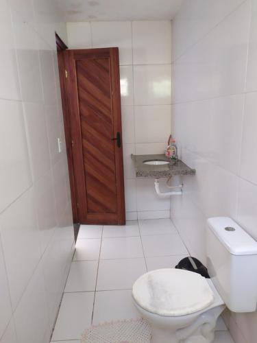 łazienka z toaletą i drewnianymi drzwiami w obiekcie Casa de praia w mieście Luis Correia