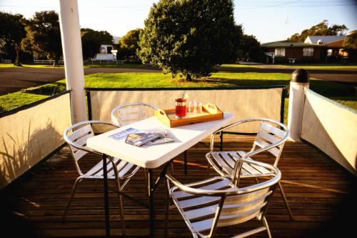 a table and four chairs on a porch with a table and chairs at Rayville Boat Houses in Apollo Bay