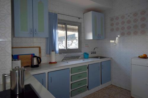 une cuisine avec des armoires bleues et un ordinateur portable sur le comptoir dans l'établissement Vista Castillo Apartments, à Alora