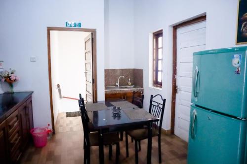 a kitchen with a table and a blue refrigerator at Seyru in Kandy