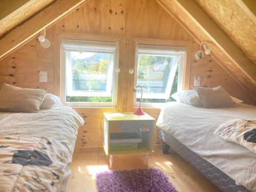 um quarto com 2 camas e um candeeiro numa mesa de cabeceira em Refugio Costa Lenca em Lenca