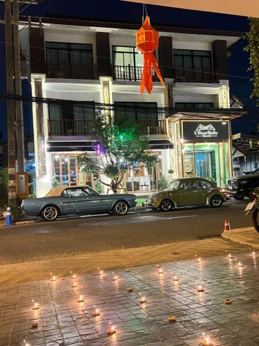 two cars parked in front of a building at night at Baannalin Hometel บ้านนลิน โฮมเทล in Chiang Mai