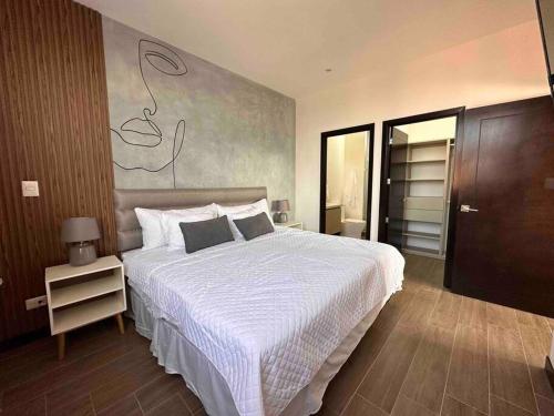 a bedroom with a large bed with a white comforter at New Modern Apartment near Mall in Guatemala