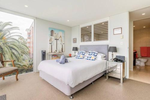 um quarto com uma grande cama branca e uma cadeira em Balmoral Beach Beauty em Sidney