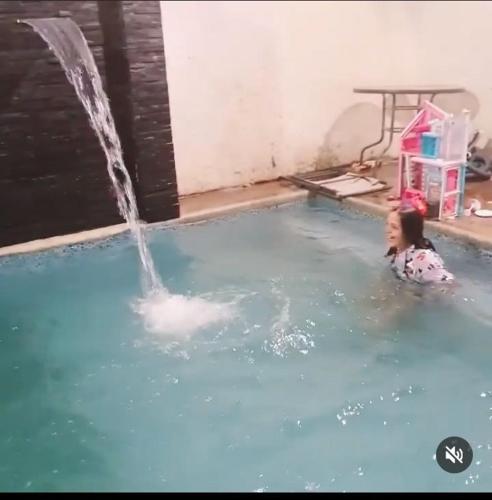una niña pequeña en una piscina con una fuente en Duran casa con piscina un solo ambiente, en Guayaquil