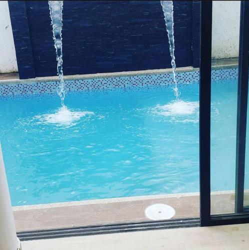 una piscina con 2 fuentes en el agua en Duran casa con piscina un solo ambiente, en Guayaquil