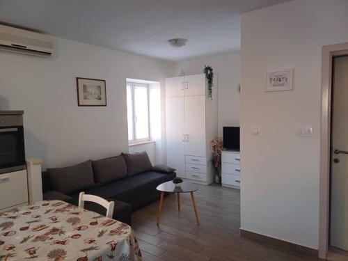 een woonkamer met een bank en een tafel bij Apartment Perica - 10 m from sea in Postira
