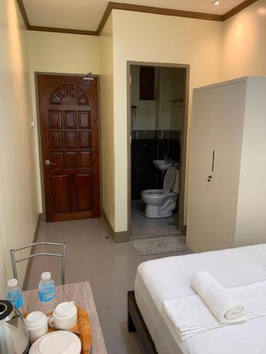 a bedroom with a bed and a bathroom with a toilet at ZL TRAVELERS INN in Batuan