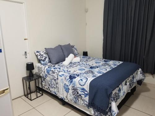 1 dormitorio con 1 cama con edredón azul y blanco en Kiaatplace Holiday Apartment, en Kingsborough