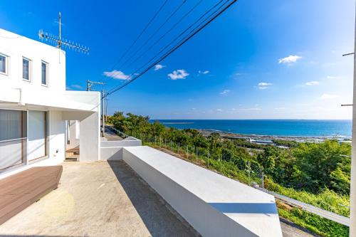 a white house with a view of the ocean at Sunrise Vista Nanjyo -SEVEN Hotels and Resort- in Nanjo