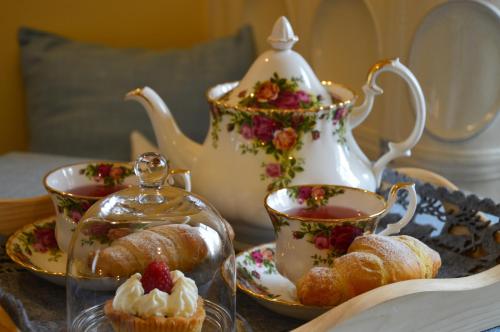 a table topped with cups and pastries and a tea pot at Hotel Garnì Carpe Diem in Vigo di Fassa
