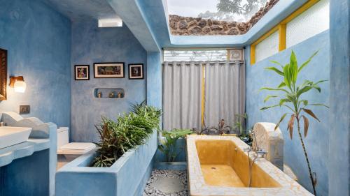 a bathroom with blue walls and a tub with plants at Aphrodite Homestays Coorg by The Almanac in Napoklu