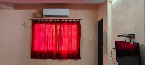 a room with a red curtain and a television at OYO SRIVARI PREMIUM HOMESTAYS in Vellore